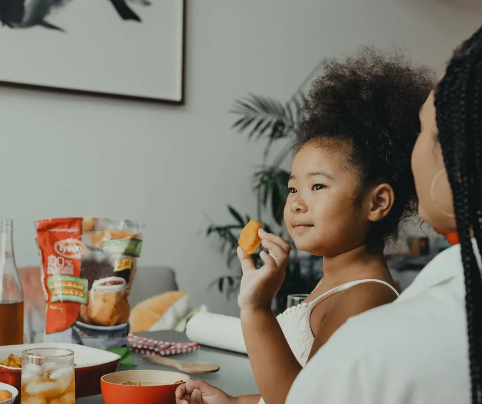 A mother is watching her daughter having meals