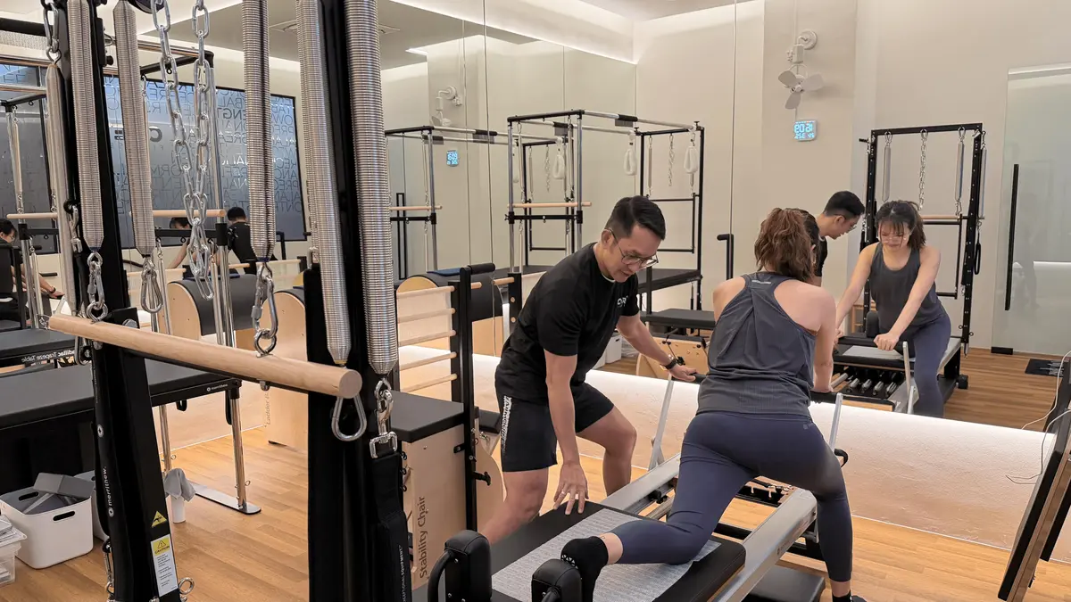 Pilates instructor guiding client on doing lunges on a reformer