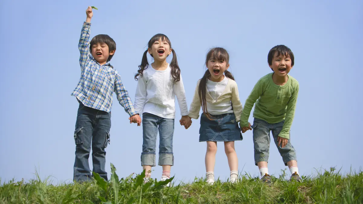 Children holding hands and happily laughing on a field